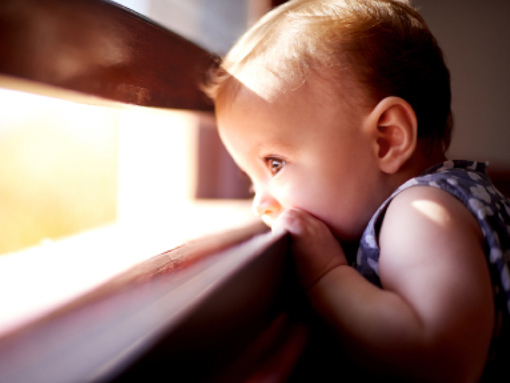 toddler with mouth on window sill